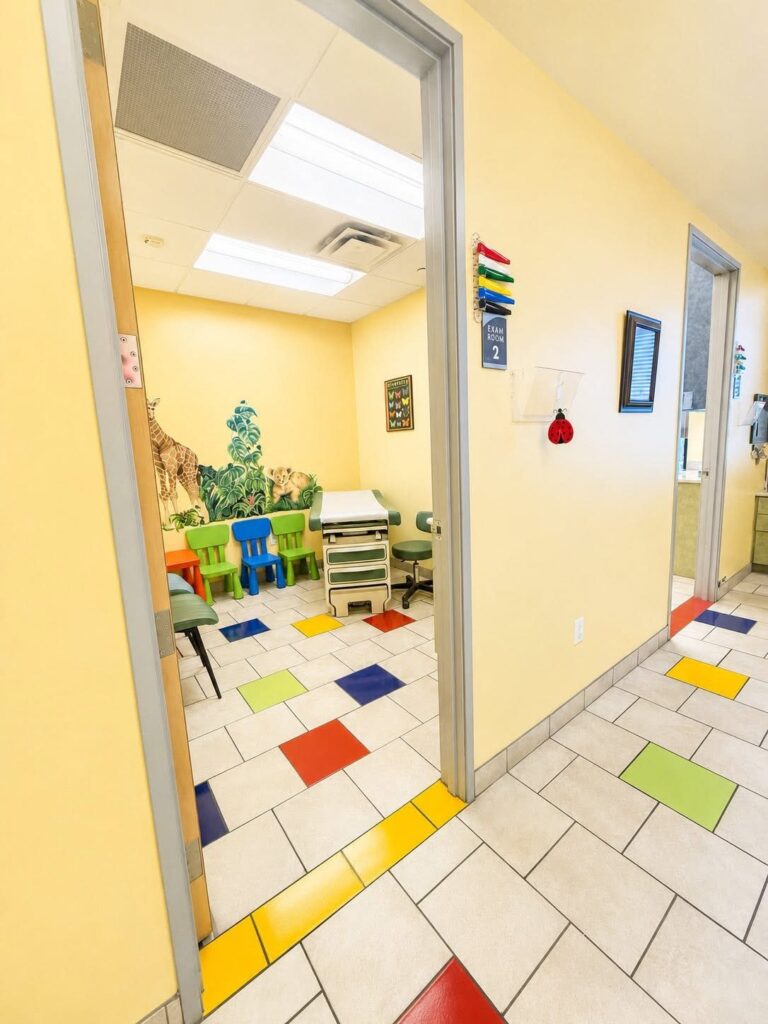 An exam room with a giraffe mural, seen from the hallway