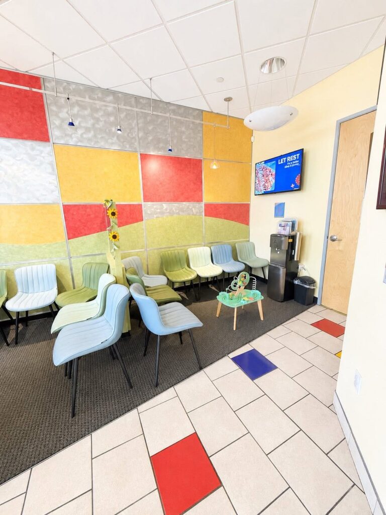 The waiting room, with colourful floor tiles and a play table